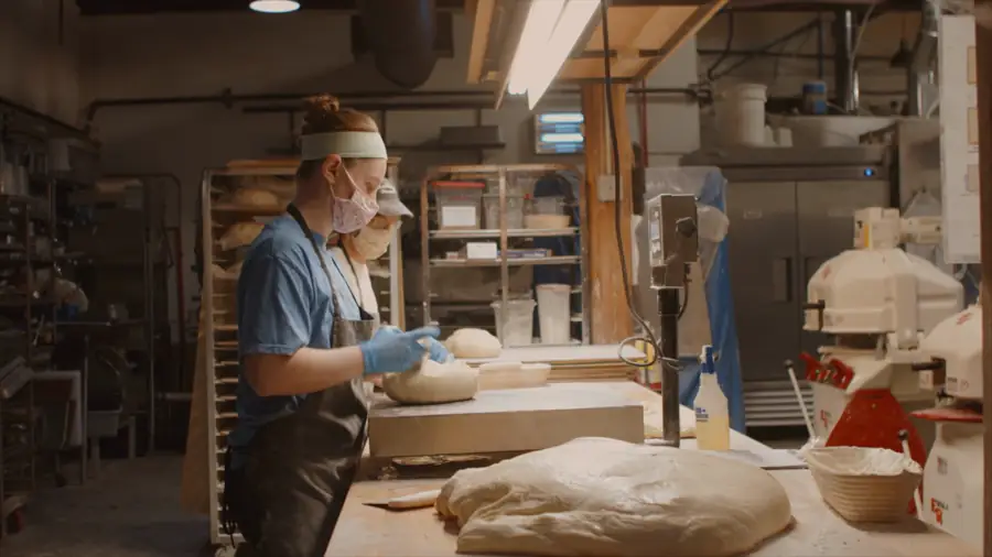Une boulangère façonnant de la pâte en fournil